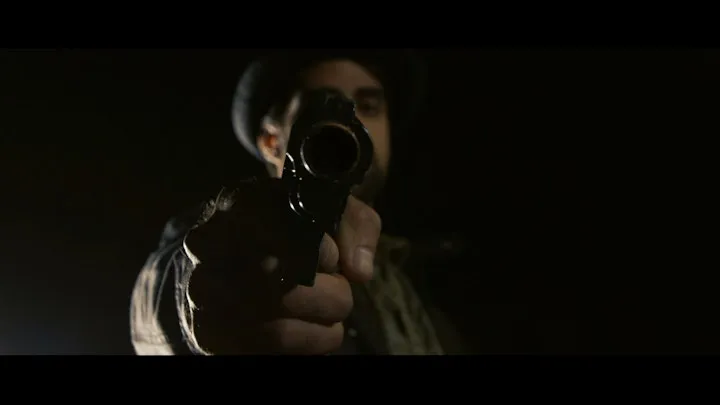 A masked figure looks towards the camera.