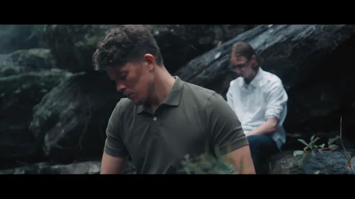 A survivor carrying a backpack moves through an open landscape.