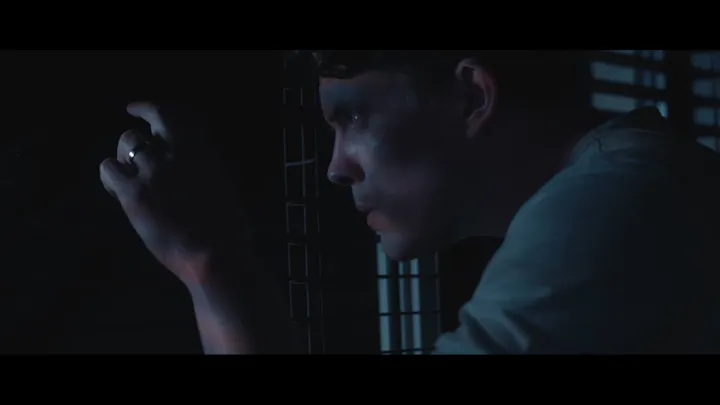 A man stands in deep shadow at night.