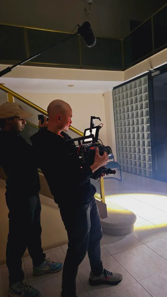 A camera operator filming through a doorway.