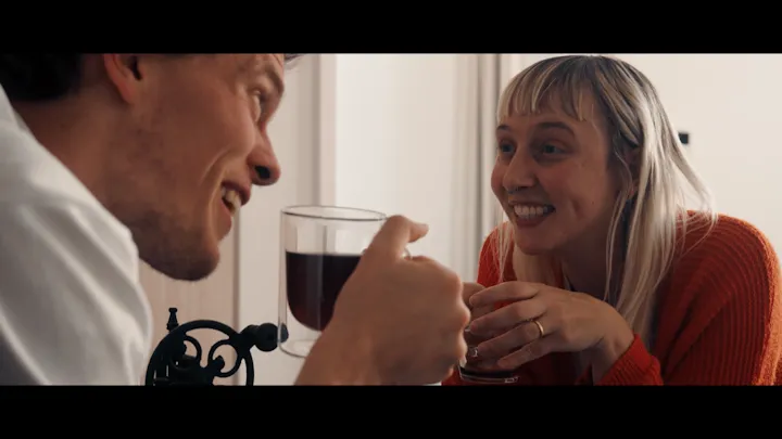 Two people talk across a table over coffee.