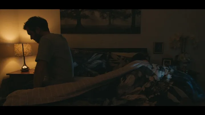A man sits alone in a dim interior.