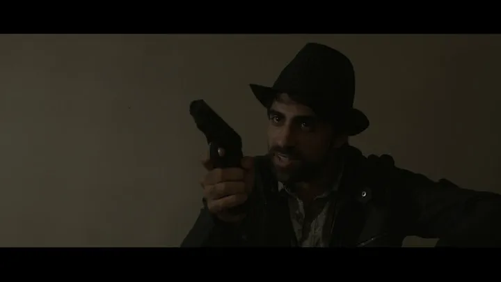 A silhouetted figure approaches someone inside a dark room.