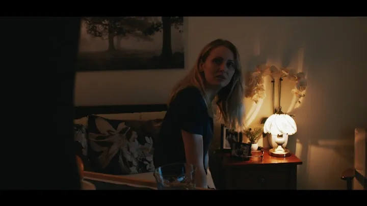 A woman sits beside a glowing table lamp.