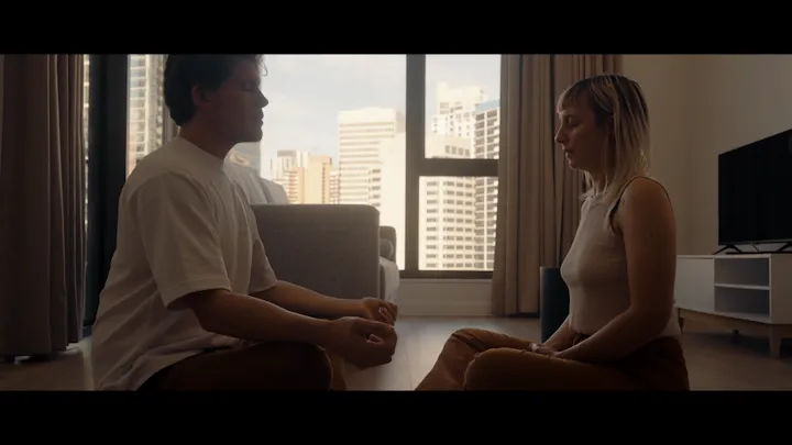 A man and woman share a quiet conversation by a window.