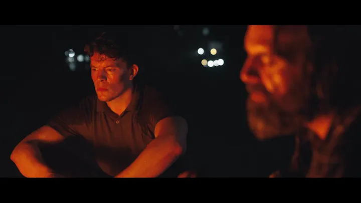 Two men are illuminated by a warm orange light.