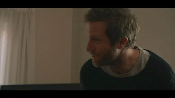 A man waits in a softly lit room.
