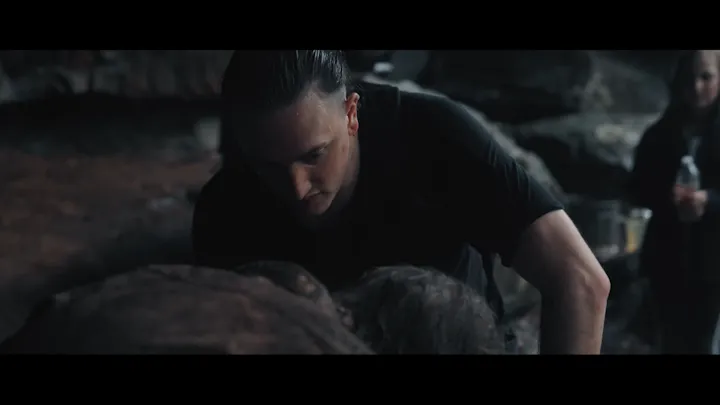 An exhausted man looks down while standing outdoors.